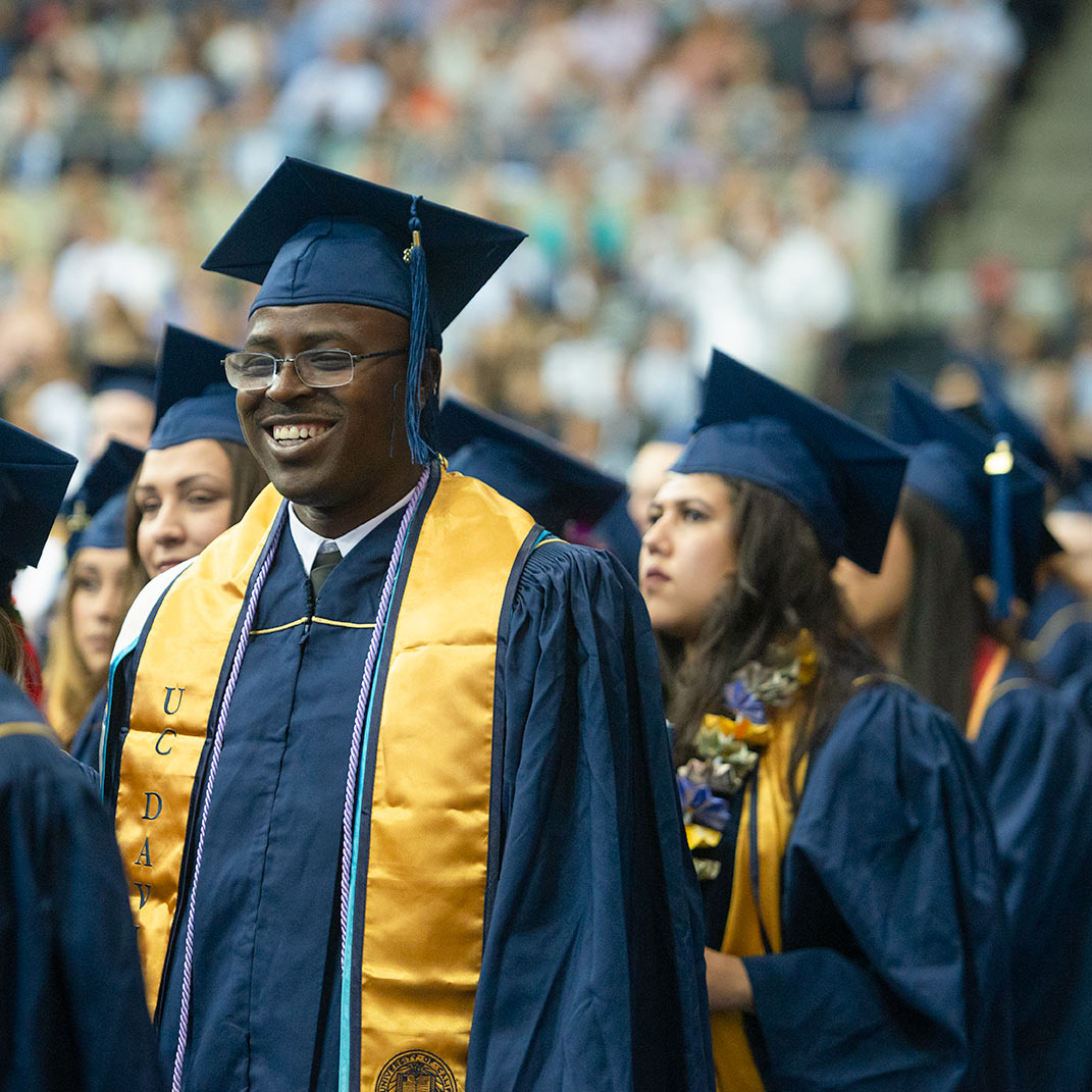 "A student smiling during commencement"