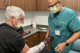 Doctor fitting person with prosthetic arm