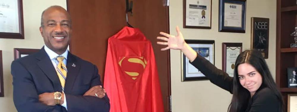 Teddy Cruz pointing to Chancellor Gary S. May's Superman cape.