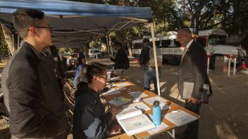 Anthony Nguyen, a biological science major, and Bryan Heng, a biology major, greet UC Davis Chancellor Gary May when he dropped by to thank them for their work during the BloodSource blood drive on the Quad on Tuesday November 7, 2017.