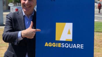 Mayor Steinberg poses for a photo next to the Aggie Square poster on the UC Davis Health campus.