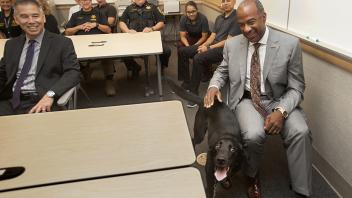Chancellor Gary May sits next to an excited bomb detection dog as he meets with the UC Davis Police Department