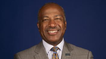 A portrait of Chancellor Gary May in front of a dark blue background