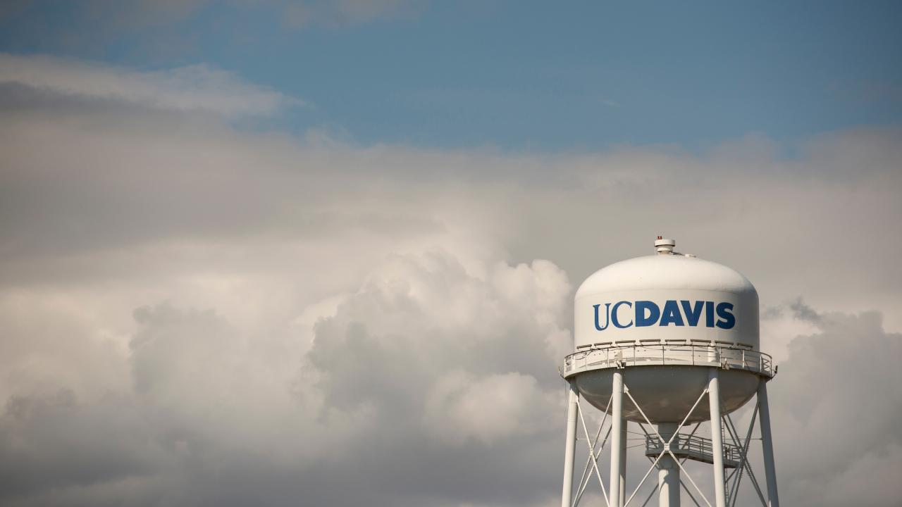 UC Davis water tower against a backdrop of fluffy clouds.