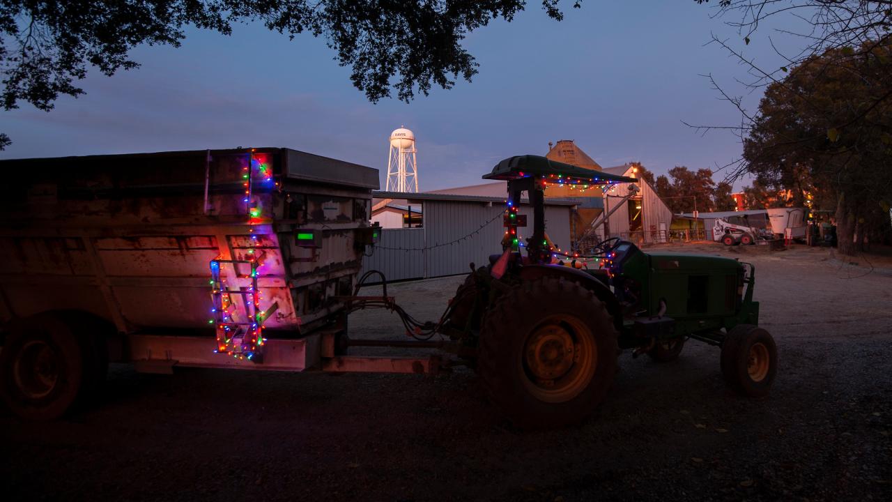 Tractor with holiday string lights on it against a backdrop of the water tower.