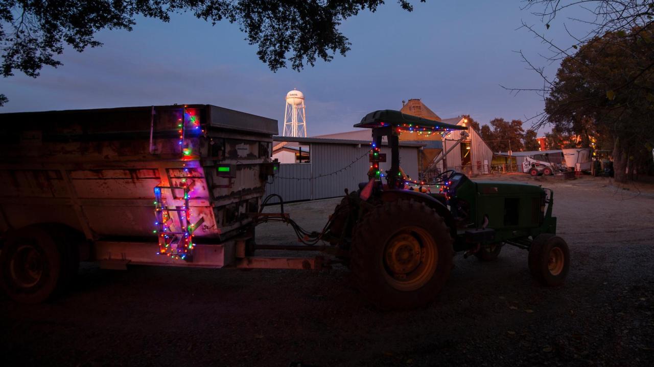 Tractor with holiday string lights on it against a backdrop of the water tower.