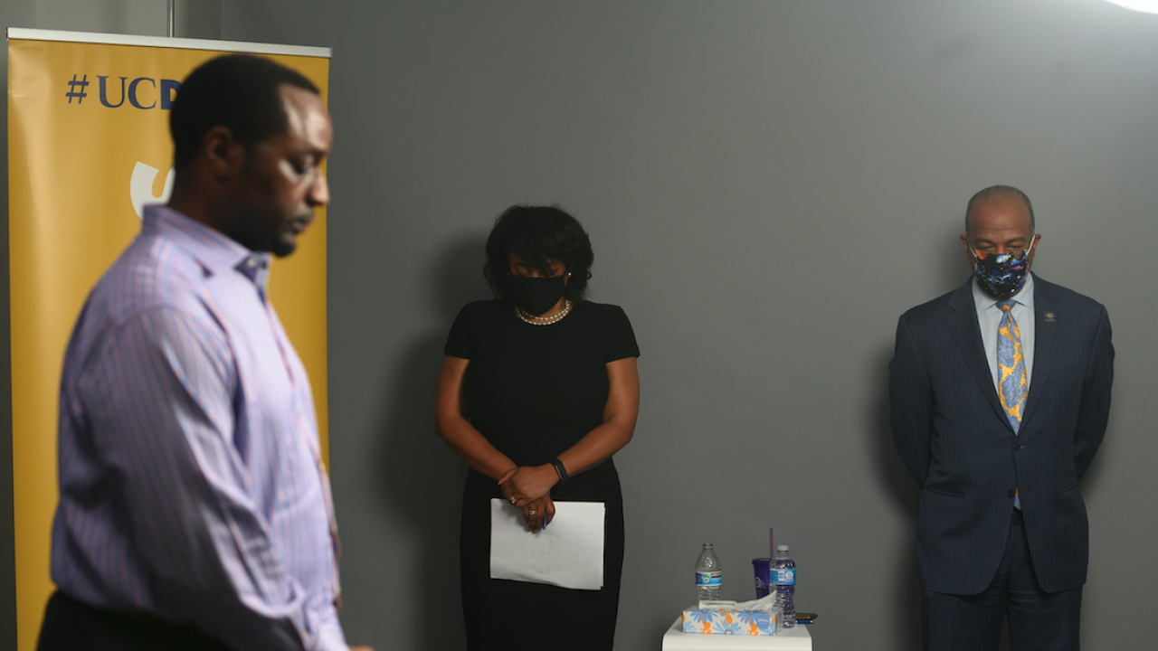 Kayton Carter, Renetta Garrison Tull and Chancellor May stand together in a moment of silence. 