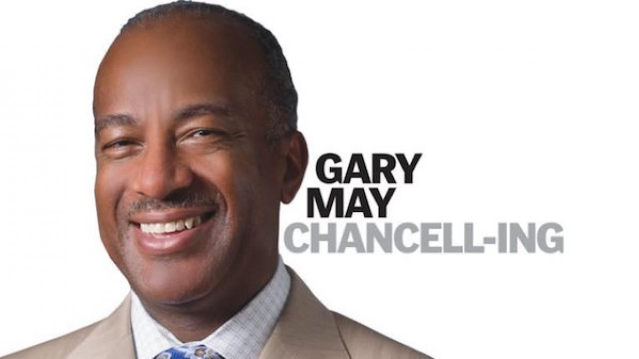 Chancellor Gary May smiling, looking at camera on white background. Words "Gary May Chancell-ing" is overlaid on the white background.