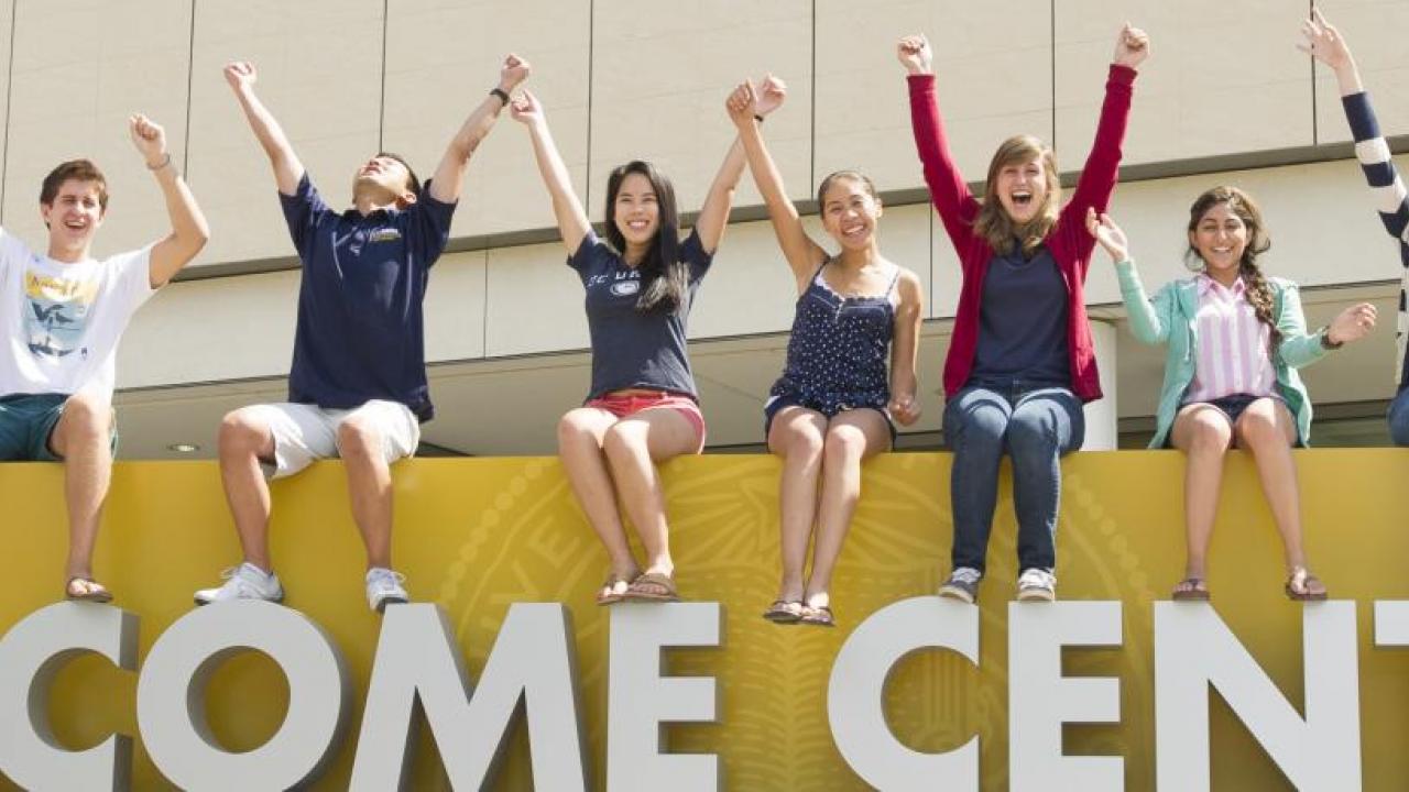 Students sit on top of giant letters reading WELCOME at UC Davis Welcome Center