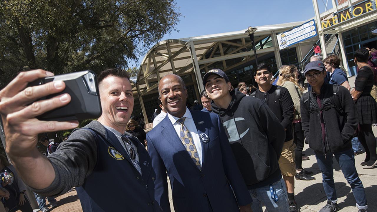 The Chancellor poses outside with a group of students at a Welcome Event in front of the Memorial Union.
