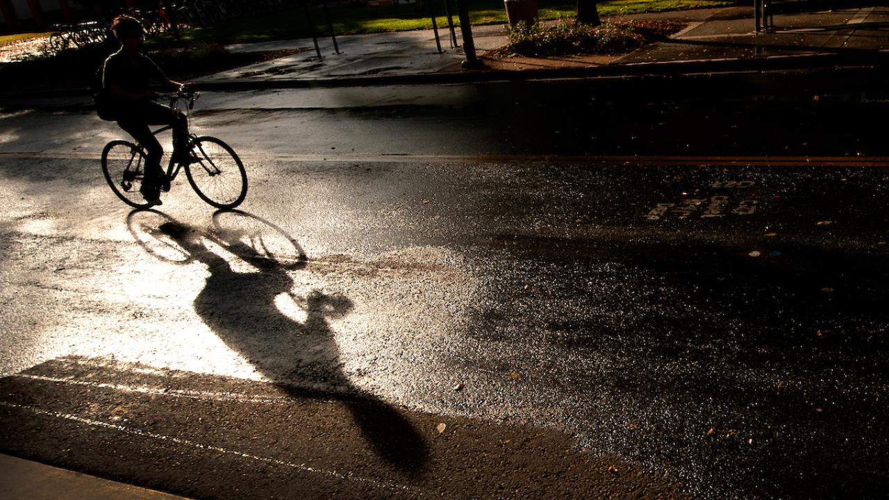 Student rides bicycle on campus after the rain in the sun