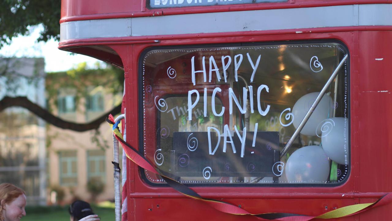 Red double decker bus with "Happy Picnic Day!" on the window