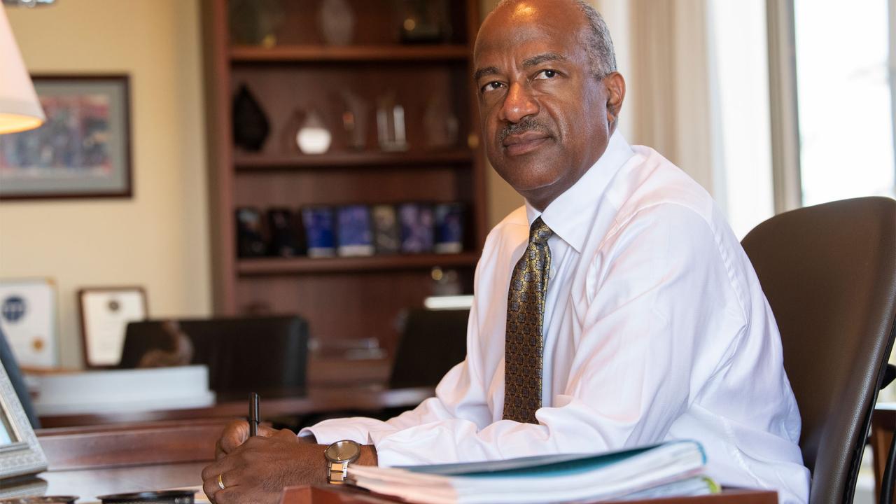 Chancellor May in his office at desk looking into the distance thoughtfully.