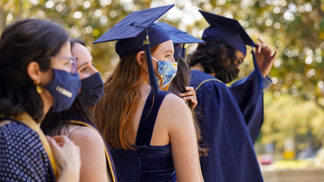 Students wearing grad caps and face coverings.