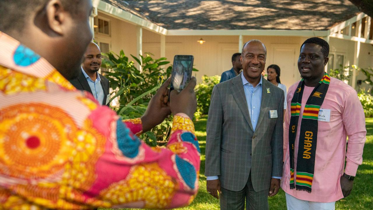 Mandela fellow taking a photo of Chancellor May and another Mandela fellow outdoors.