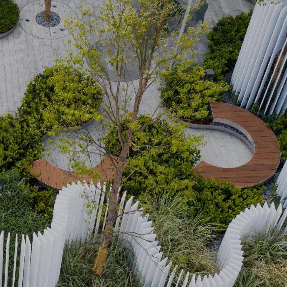 An exterior landscape deisgn with wavy fence like structures and sitting areas