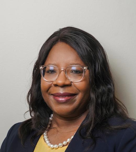 Dean Estella Atekwana wearing blazer, yellow top, pearl necklage and glasses.