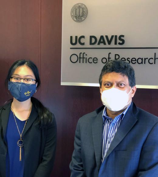 Two people stand in front of a sign that says UC Davis Office of Research