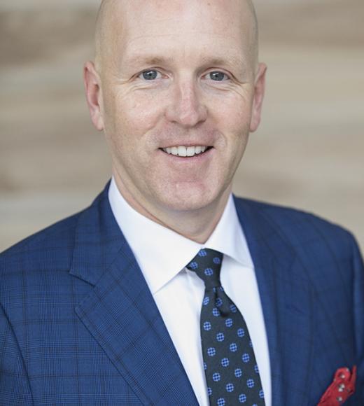 headshot of Toby wearing a blue suit