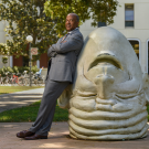 Chancellor May leaning on an Egghead in front of Mrak Hall. 