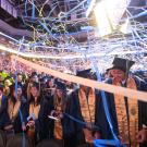 UC Davis students celebrate spring 2024 commencement with blue and gold streamers above them.