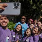 Students holding camera phone taking selfie with Chancellor May