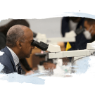 Chancellor May looks through a microscope